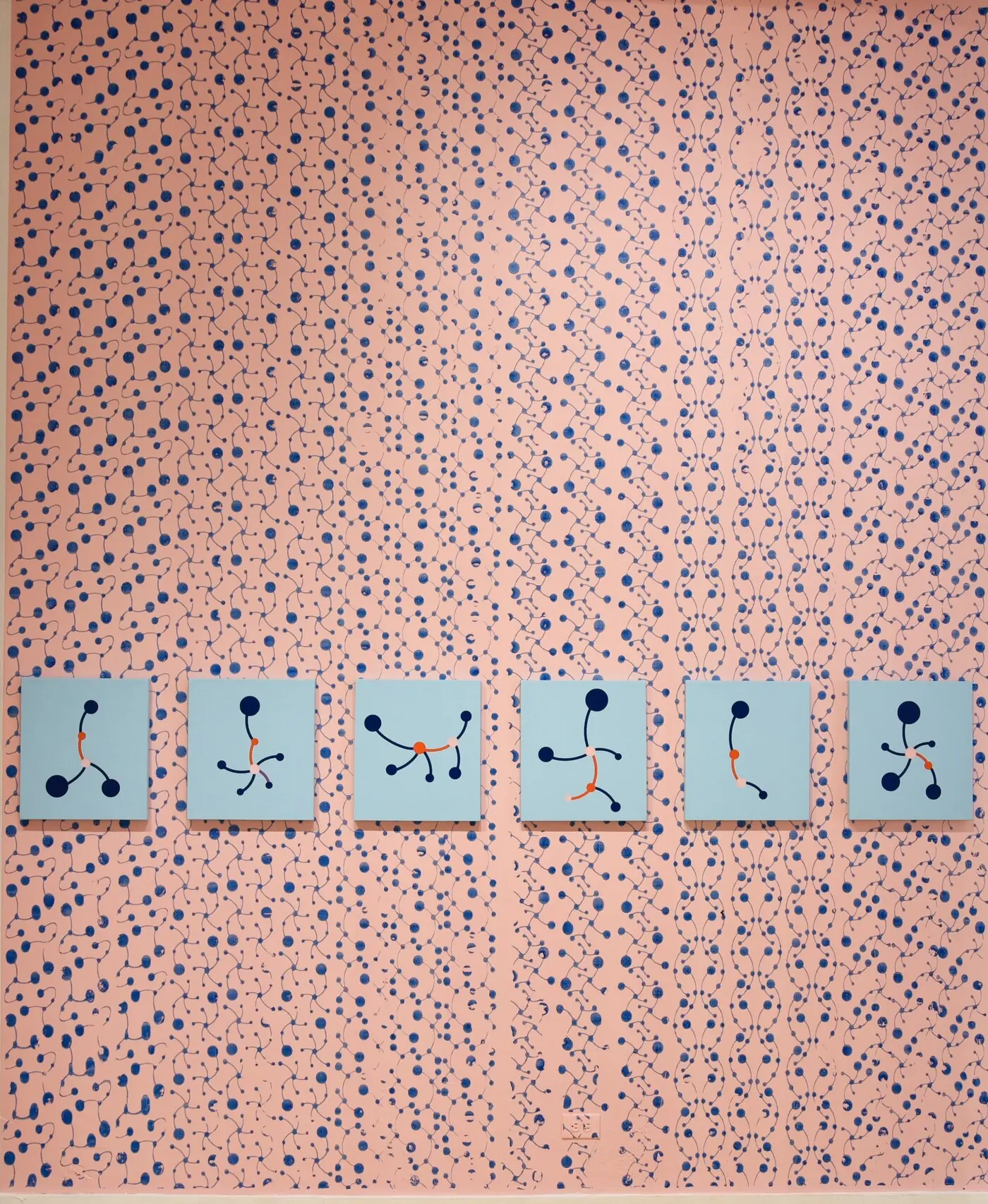 Pink wall printed by roller with blue networks, with six small blue network paintings in a row