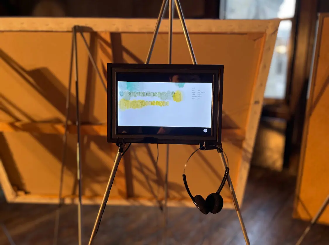 Bestselling Books Project on a framed screen on an easel, with headphones, at London Design Festival