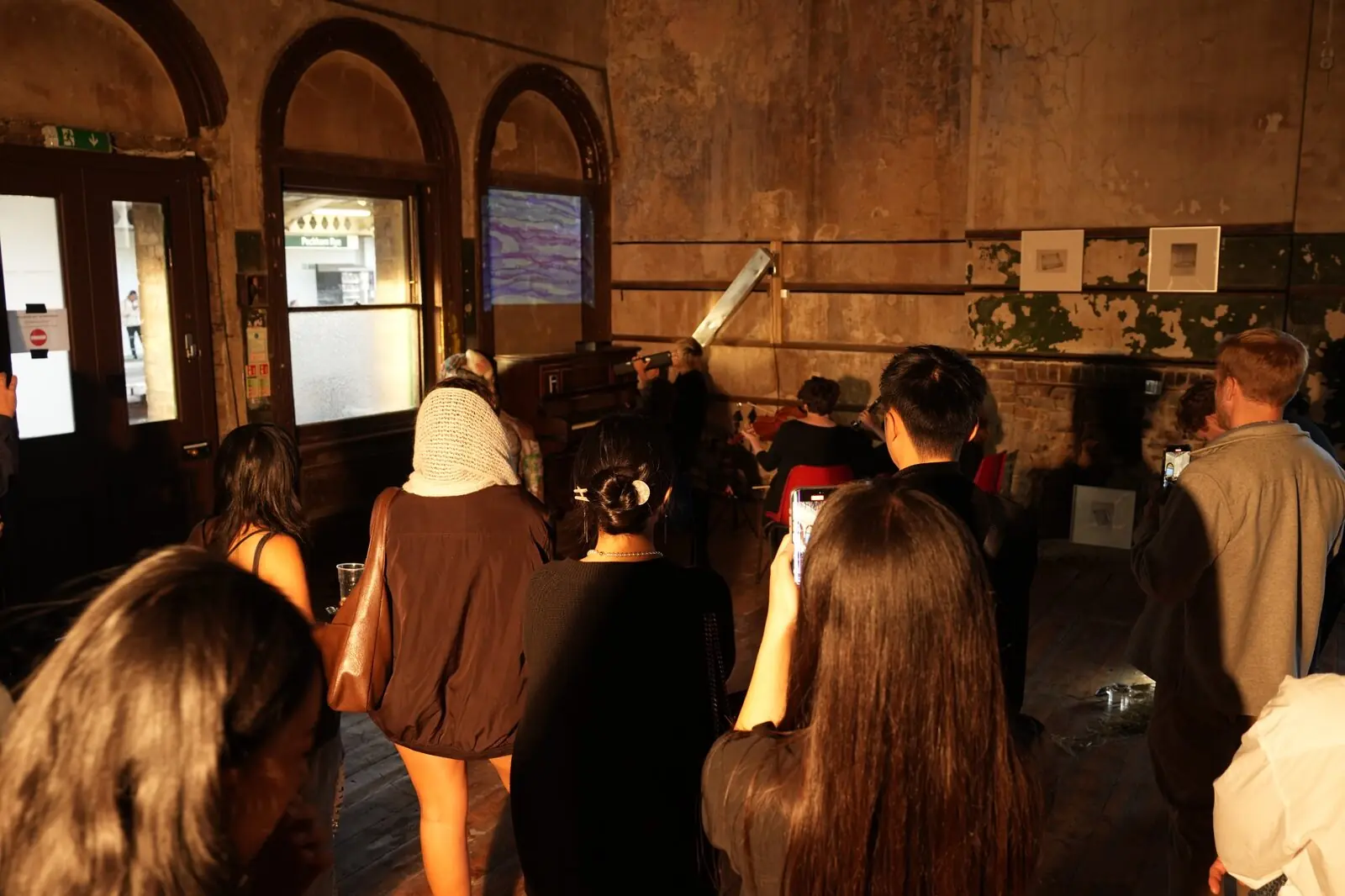 Visitors at the London Design Festival exhibition in a room with arched windows